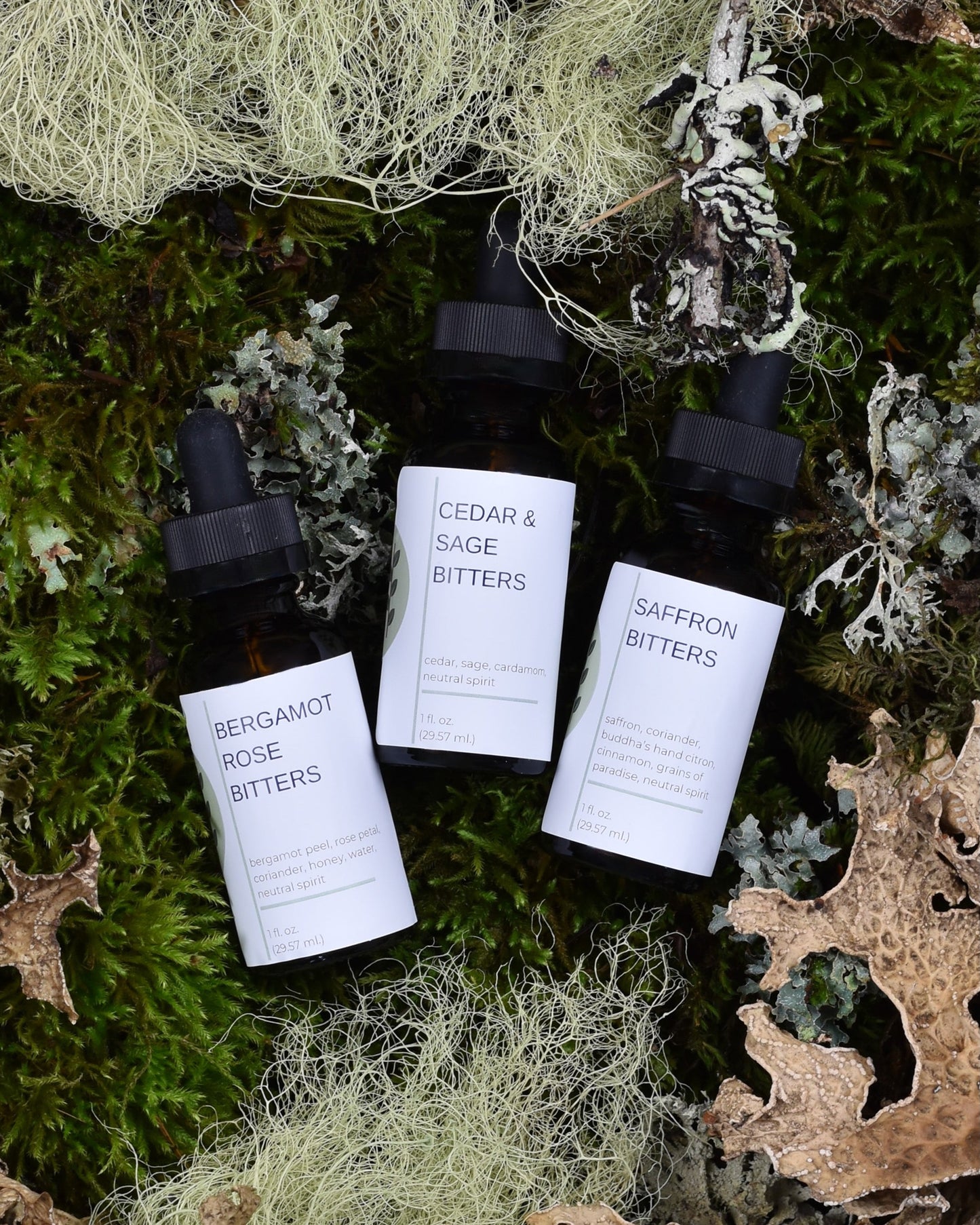 FreeWildShe Limited Bitters Collection featuring Bergamot Rose, Cedar & Sage, and Saffron lay on a bed of moss & lichen.