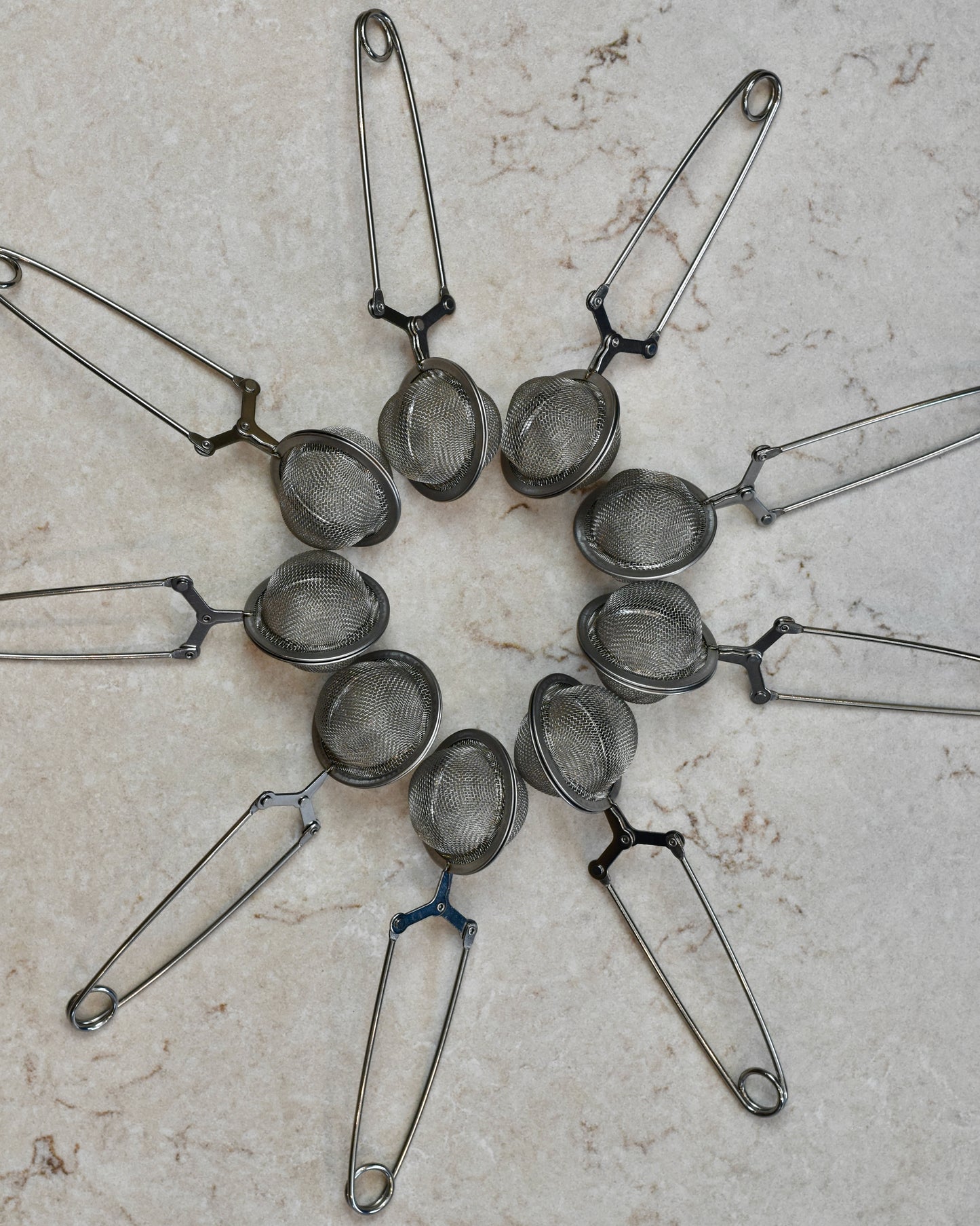 FreeWildShe Squeeze Infusers lay around in a circle with their handles pointing outward, on a cream colored countertop.
