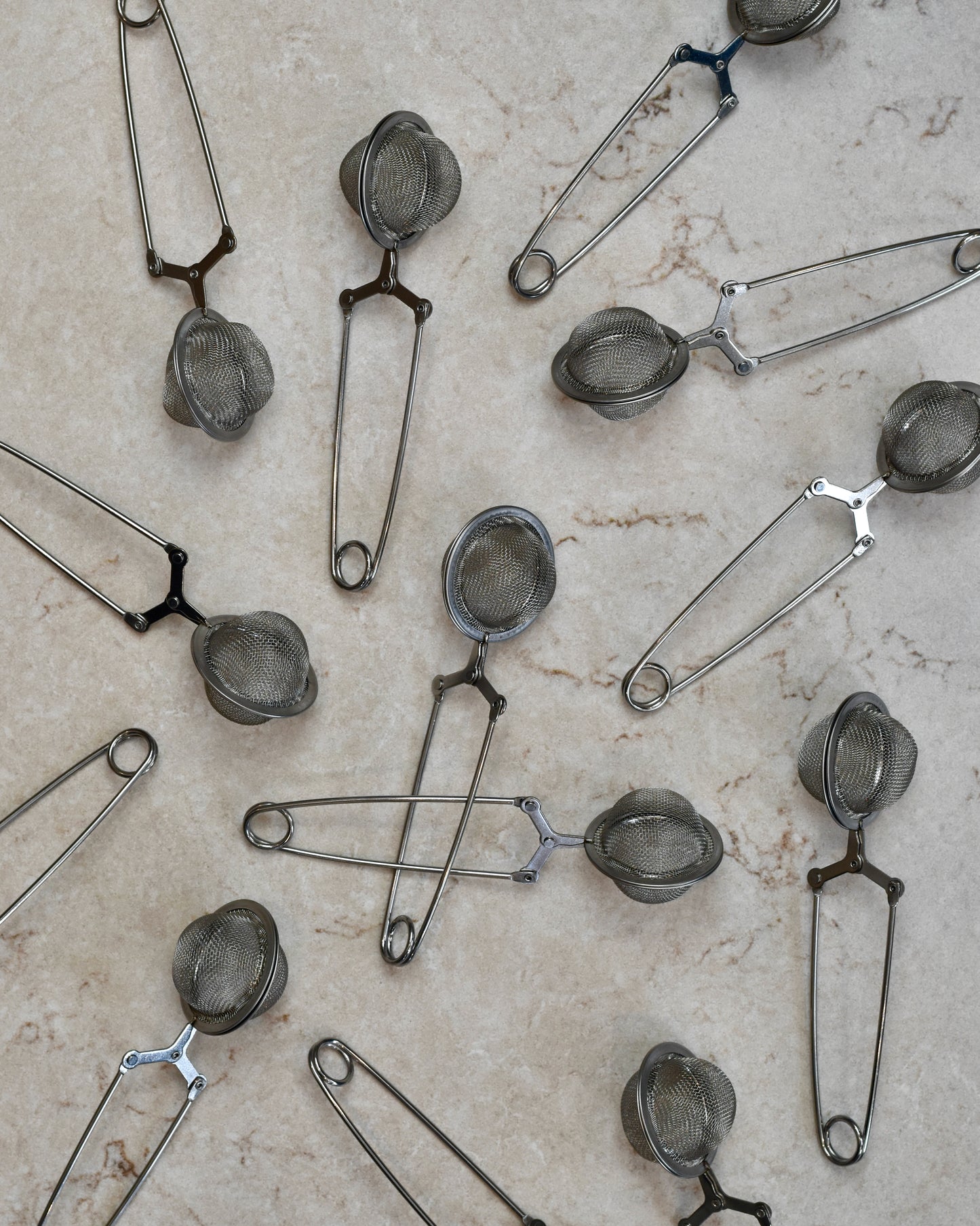 FreeWildShe Squeeze infusers with a handle lay scattered on a cream countertop.