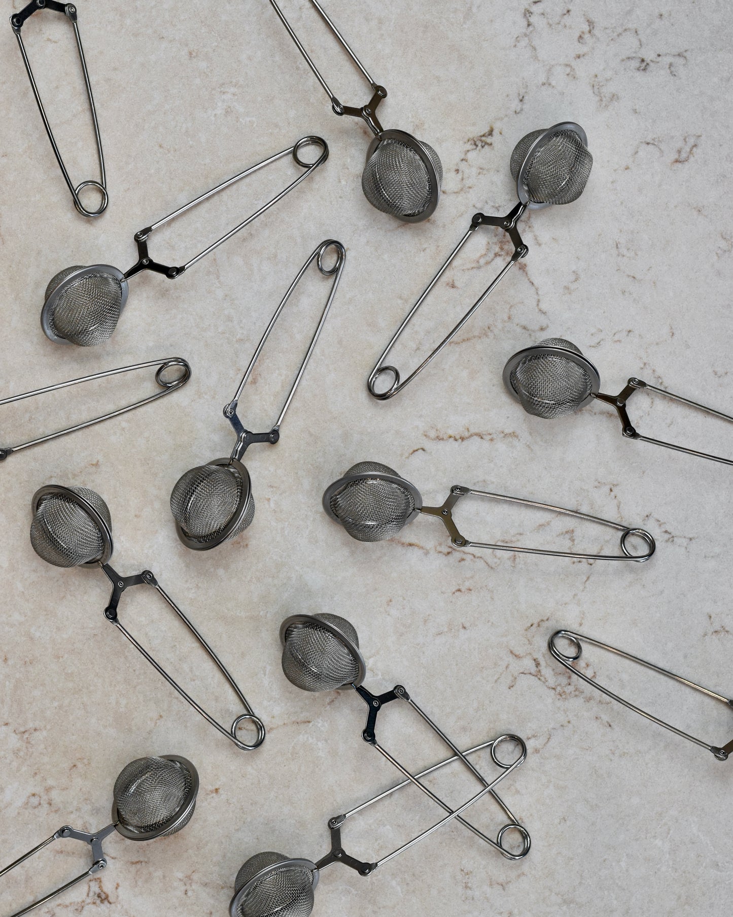 FreeWildShe Squeeze infusers with a handle lay scattered on a cream countertop.