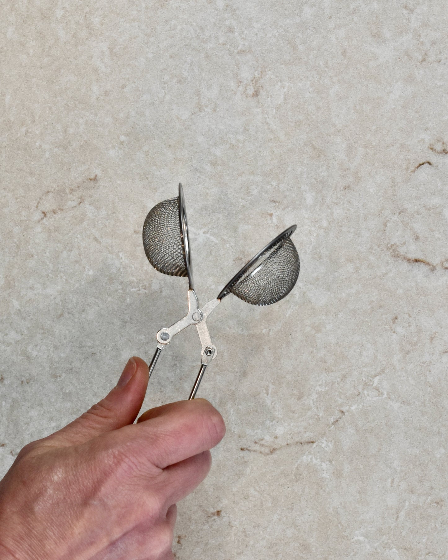 Someone is squeezing the handle of a FreeWildShe Squeeze Infuser to show how to open it up.