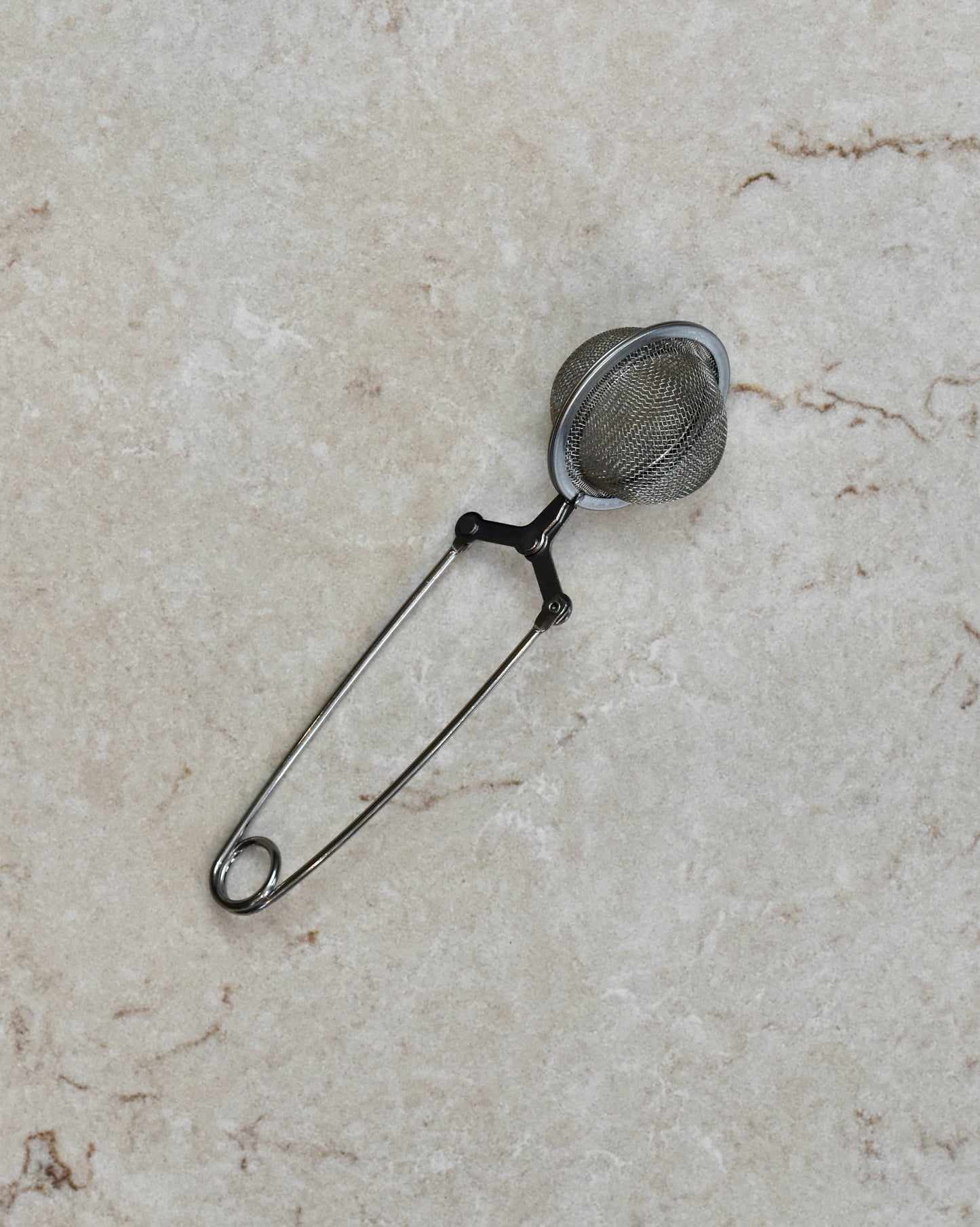 A FreeWildShe Squeeze Infuser with a handle lays in the center of a cream colored countertop.