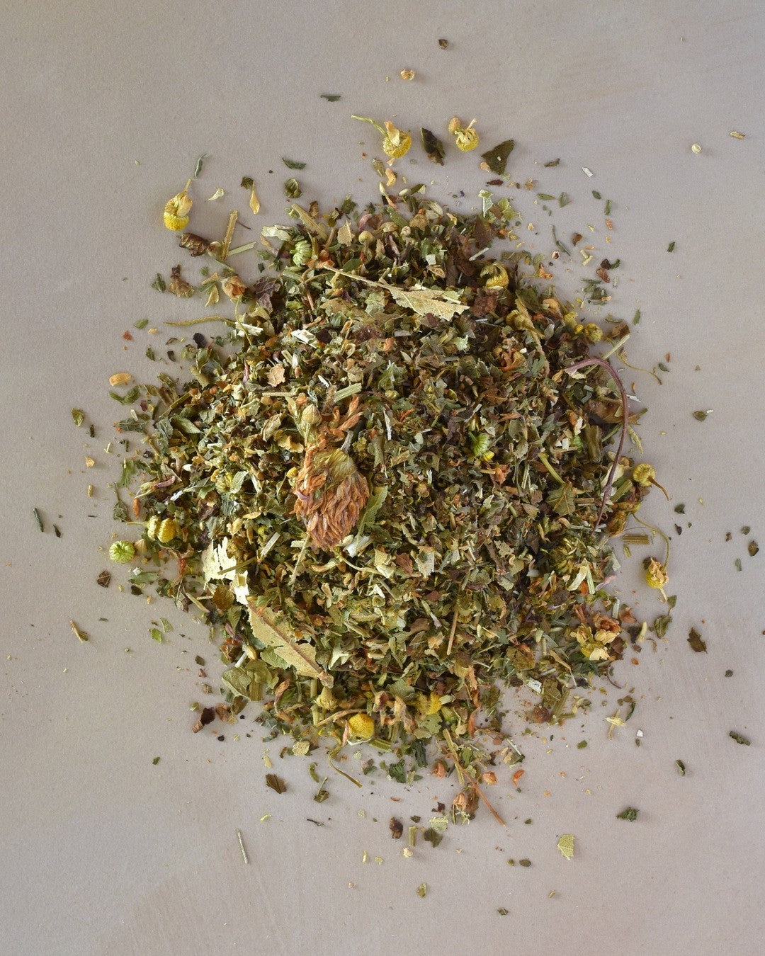 FreeWildShe Calm Herbal Tea loose leaf ingredients lay in a pile on a cream countertop.