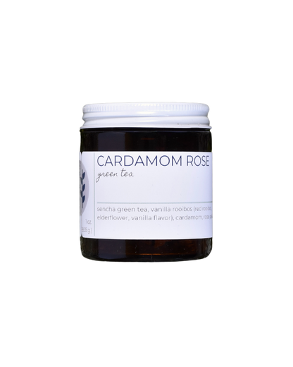 A 20 serving jar of FreeWildShe Cardamom Rose Green Tea. The jar is dark brown, the lid is white metal, the label is white with navy & gray text. The background is transparent.