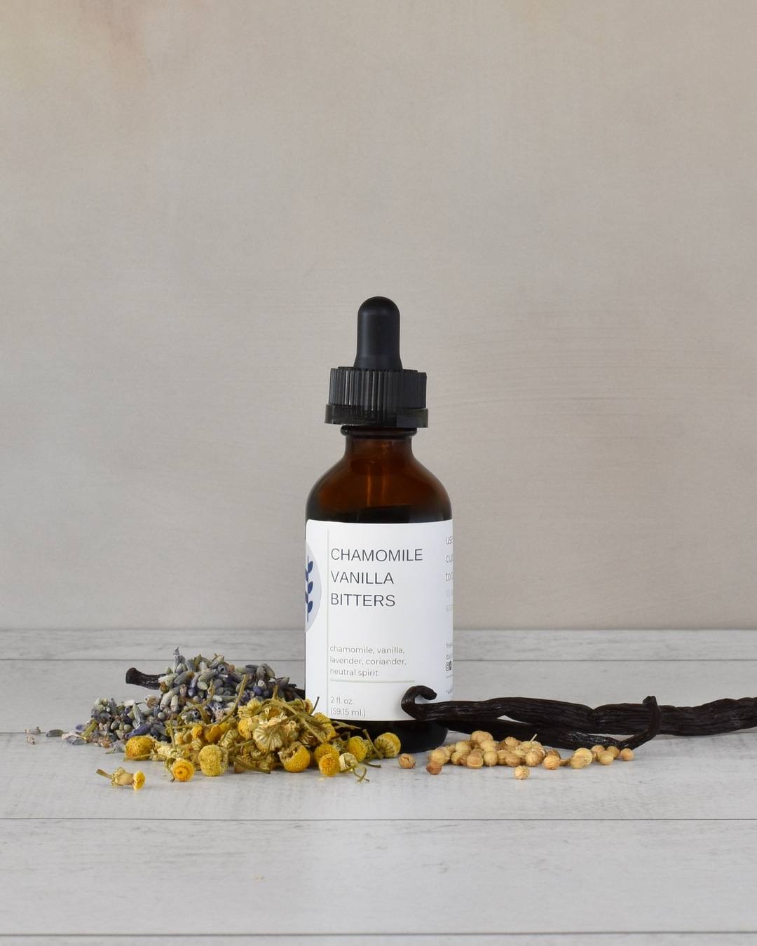 FreeWildShe Chamomile Vanilla Bitters sit on a white countertop surrounded by ingredients.