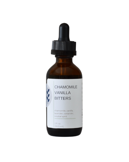 A bottle of FreeWildShe Chamomile Vanilla Bitters. The bottle is brown, the dropper top is black, and the label is white with navy & gray text. The background of the image is transparent.