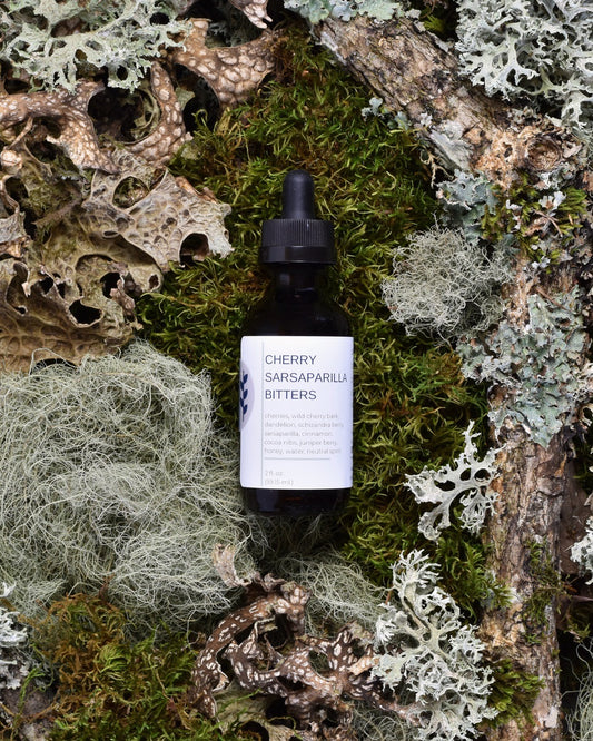 FreeWildShe Cherry Sarsaparilla Bitters sit on moss & lichen.