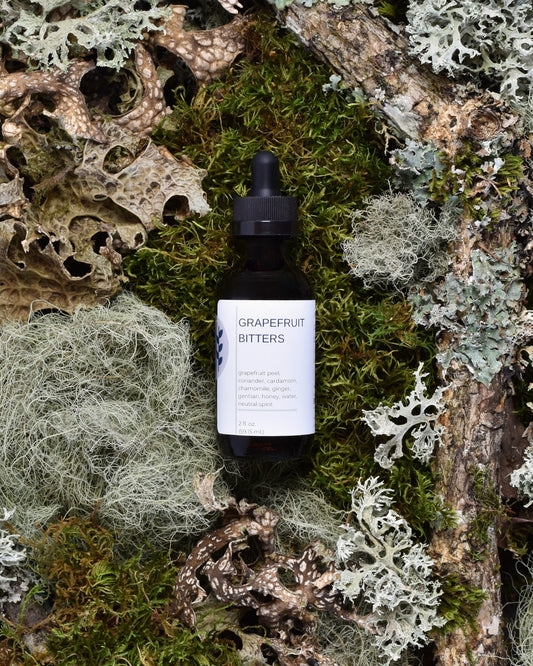 FreeWildShe Grapefruit Bitters sit on moss & lichen.