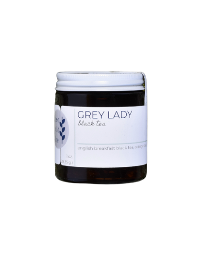 A 20 serving jar of FreeWildShe Grey Lady Black Tea. The jar is dark brown, the lid is white metal, the label is white with navy & gray text. The background is transparent.