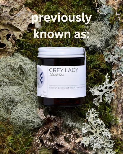 Text at the top of the image reads 'previously known as'. A FreeWildShe jar of tea sits moss & lichen. The label reads Grey Lady Black Tea.