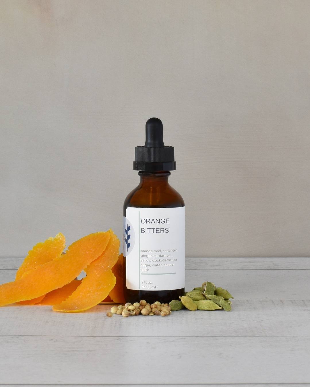 FreeWildShe Grapefruit Bitters sit on a white countertop surrounded by ingredients.