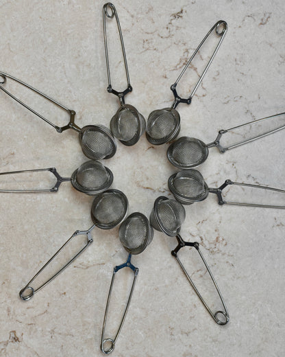 FreeWildShe Squeeze Infusers lay around in a circle with their handles pointing outward, on a cream colored countertop.