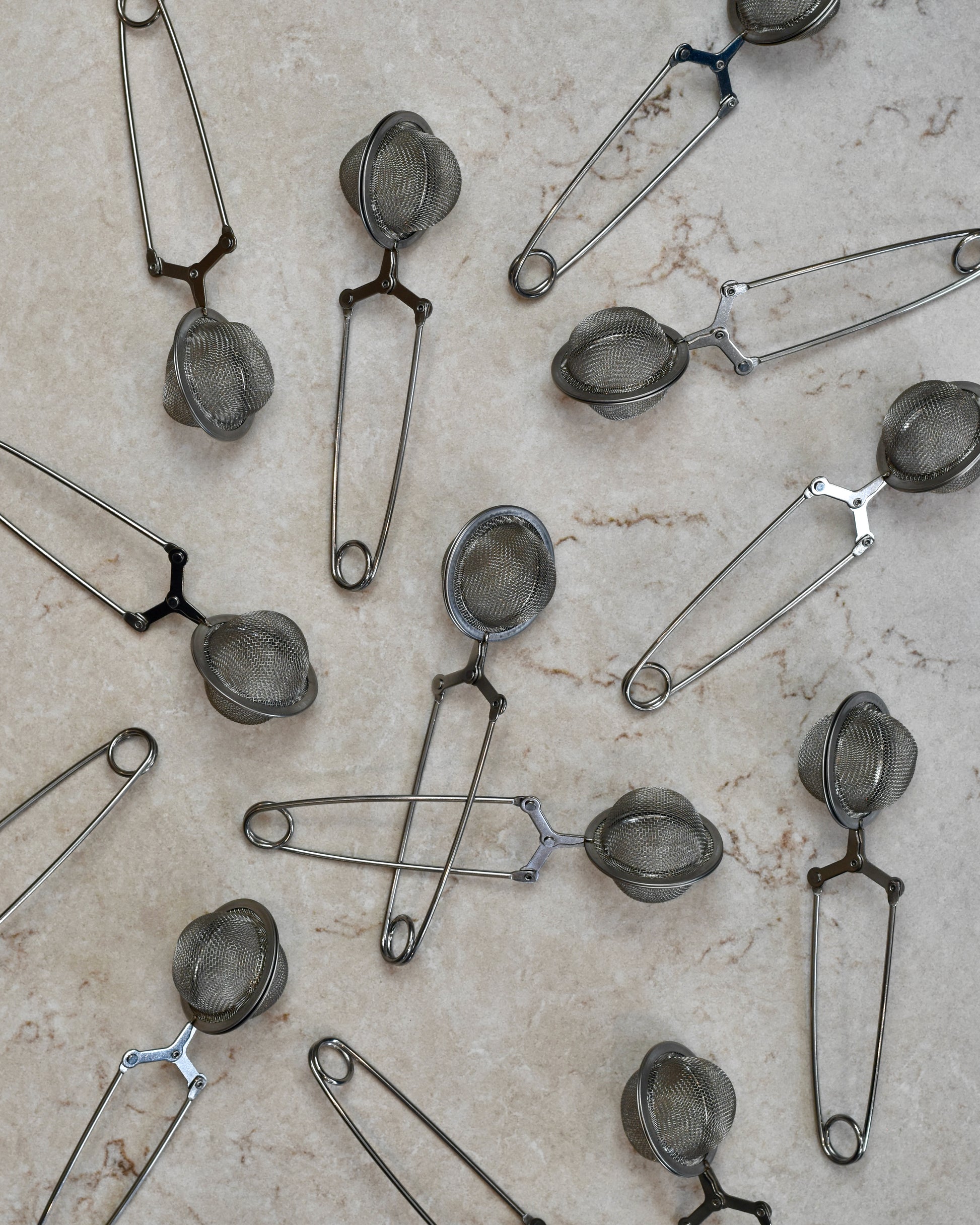 FreeWildShe Squeeze infusers with a handle lay scattered on a cream countertop.