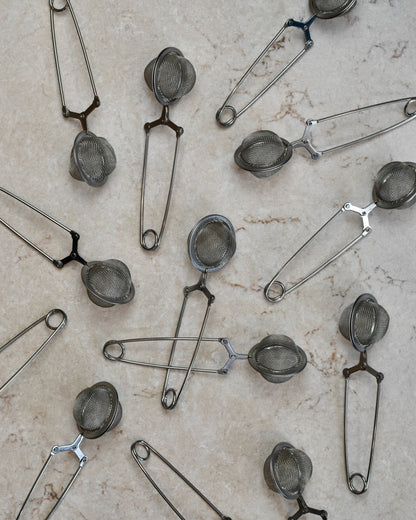 FreeWildShe Squeeze infusers with a handle lay scattered on a cream countertop.