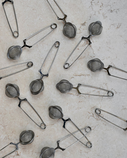 FreeWildShe Squeeze infusers with a handle lay scattered on a cream countertop.